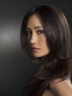 a woman with long dark brown hair is posing for a photo in front of a black background