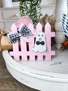 a pink fence with two ghost decorations on it and a plant in the back ground