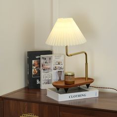 a table lamp sitting on top of a wooden dresser next to a stack of books