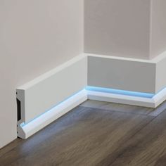 the corner of a room with wood flooring and white walls is illuminated by blue leds