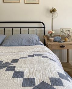 a bed with blue and white bedspread next to a night stand in a bedroom