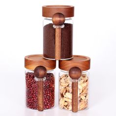 three glass jars with wooden spoons filled with nuts and dried cranberry seeds