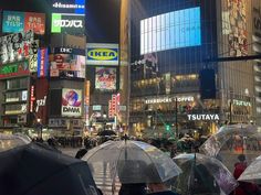 many people with umbrellas in the city at night