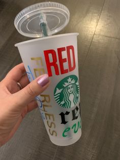 a hand holding a starbucks cup with red lettering on it