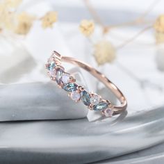 a gold ring with blue and white stones on top of a marble slab next to flowers