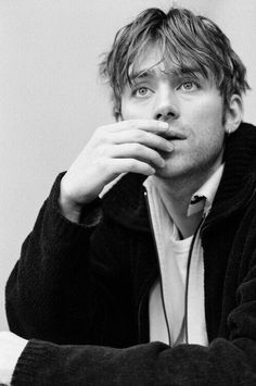 black and white photograph of a young man with headphones on his ears, leaning against a wall