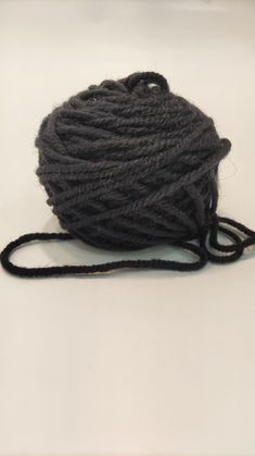 a ball of yarn sitting on top of a white table next to a black string