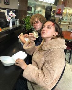 two people sitting at a table eating food