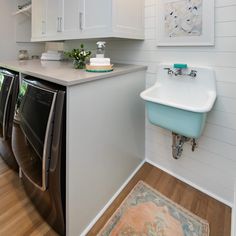 a washer and dryer in a white laundry room with wood flooring on the walls