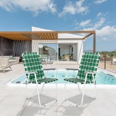 two lawn chairs sitting on top of a swimming pool next to a covered patio area