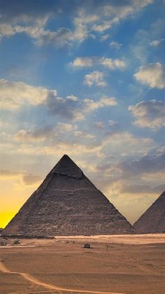 three pyramids in the desert under a cloudy sky