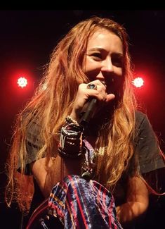 a woman with long hair holding a microphone in front of her face while standing on stage