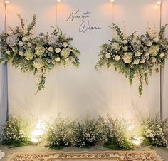 two floral arrangements on the wall at a wedding ceremony with lights in front of them