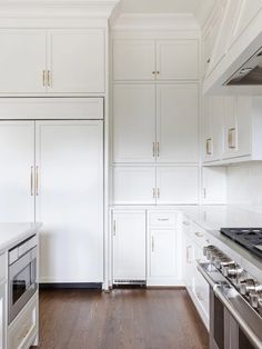 a kitchen with white cabinets and wood floors is pictured in this image, there are two ovens on either side of the counter