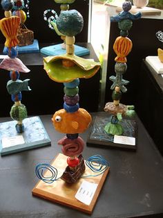 a table topped with lots of colorful glass items on top of a wooden stand next to a window