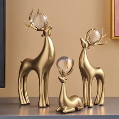 three golden deer statues sitting on top of a table