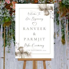 an easel with flowers and greenery on it in front of a wedding sign