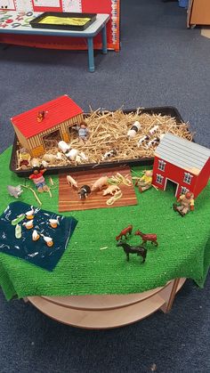 a table topped with farm animals and toys on top of a green cloth covered table