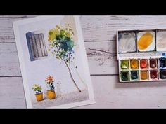 an artist's watercolor painting with paintbrushes on a white wooden table