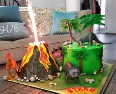 a birthday cake is decorated with dinosaurs and volcanos