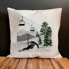 a pillow with a skier on the ski lift printed on it, sitting on a wooden table