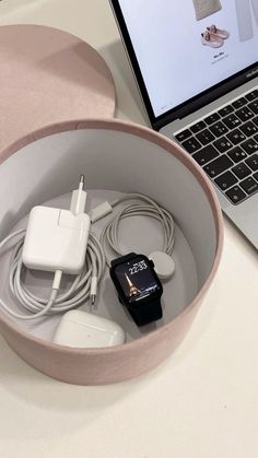 an open laptop computer sitting on top of a white table next to a bowl filled with cords