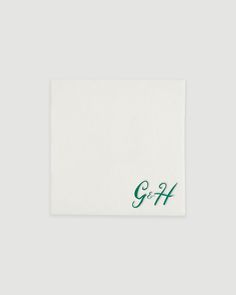 a white napkin with green lettering on the front and bottom, which reads g & h