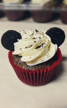 a cupcake with white frosting and mickey mouse ears on it's head