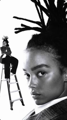 a woman with dreadlocks sitting on top of a ladder