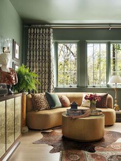 a living room filled with lots of furniture next to a window covered in green curtains