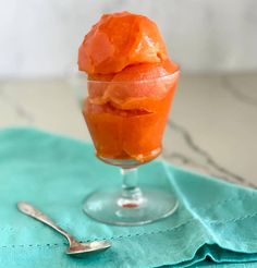 an ice cream sundae in a glass on a blue napkin next to a spoon