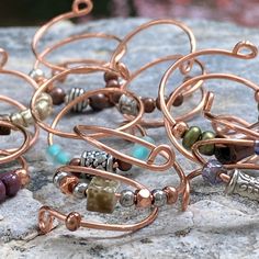 several different types of bracelets sitting on top of a rock with wire wrapped around them