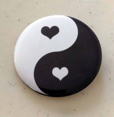 a black and white button with two hearts in the shape of a yin symbol