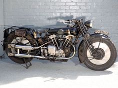 an old motorcycle parked next to a brick wall