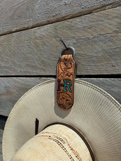 a cowboy hat hanging from the side of a wooden wall with an embroidered r on it