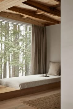 a bed sitting in the middle of a room next to a window with trees outside