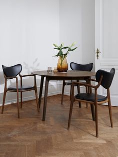 a dining table with chairs around it and a potted plant on the table top