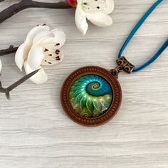 Turquoise blue wooden pendant necklace with fossil detail ammonite picture necklace. Cabochon jewellery, necklaces for women in the UK. This beautiful necklace is a round antique bronze tone  base which I've set with an emerald green ammonite fossil print glass cabochon,  it would make a perfect gift, maybe for a  birthday present. Its set on an 18 inch bright emerald green vegan suede cord, and fastens with a lobster clasp and extender chain. Gifts - If this item is a gift, please select 'gift Bohemian Spiral Necklace For Gift, Bohemian Spiral Necklace As A Gift, Bohemian Spiral Necklace As Gift, Handmade Turquoise Spiral Jewelry, Handmade Spiral Turquoise Jewelry, Unique Spiral Turquoise Jewelry, Artistic Turquoise Necklace With Round Pendant, Bronze Cabochon Necklace For Gifts, Artistic Turquoise Necklace Gift