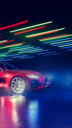 a red sports car driving down a street at night with neon lights on the walls