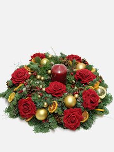 a christmas wreath with red roses, pine cones and a lit candle in the center