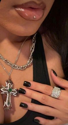 a close up of a person with black nail polish and a cross on her necklace