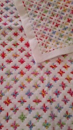 a white sheet with colorful sprinkles on it and a pink blanket behind it