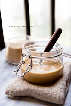 a jar filled with food sitting on top of a wooden table next to a spoon