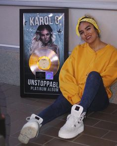 a woman sitting on the ground next to a record player and a poster with an album