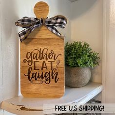 a wooden sign that says gather eat laugh on it with a bow hanging from the front