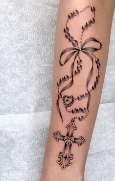 a woman's arm with a cross and rosary tattoo on it, which is decorated with pearls