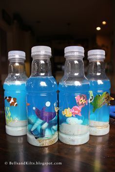 three plastic water bottles with fish and sea animals on them sitting on a wooden table