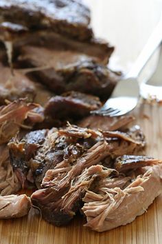 the meat is sliced and ready to be eaten on the cutting board with a fork