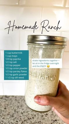 a hand holding a mason jar filled with homemade ranch seasoning and instructions for how to make it