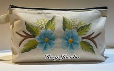 a white purse with blue flowers painted on it